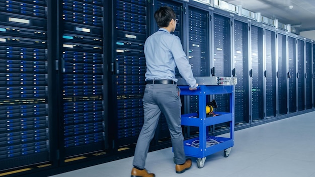 A man in a data center with a cart full of servers.
