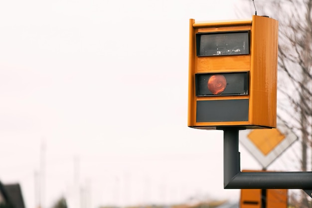 a yellow speed camera flashes as it detects a speeding car on a highway using radar and artificial intelligence to recognize the number plate and issue a fine