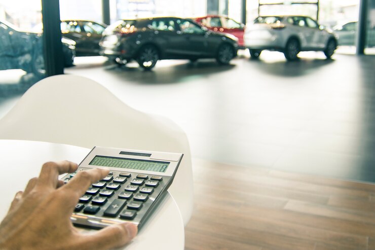 Araba showroom bulanık arka planında iş finansmanı için hesap makinesine basan Asyalı adam