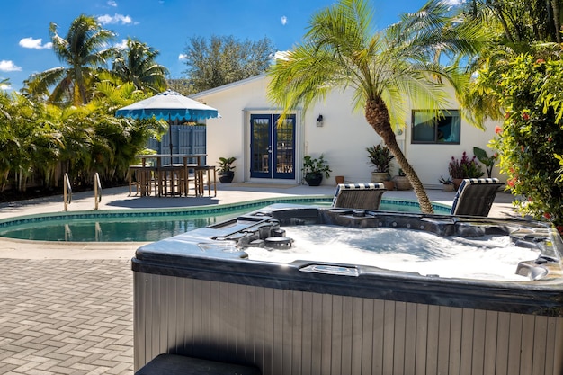 Backyard of a modern house with swimming pool artificial grass stone path trees chairs