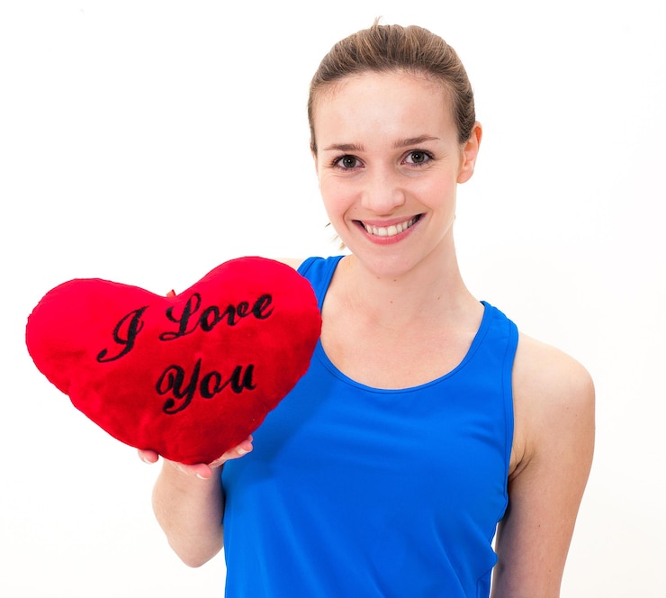 Fotoğraf beautiful woman with heart shape pillow against white background