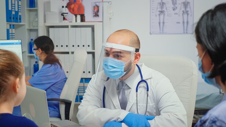 Fotoğraf child and doctor with protection mask talking and laughing in medical office during coronavirus. physician specialist in medicine providing health care services consultation treatment in hospital.