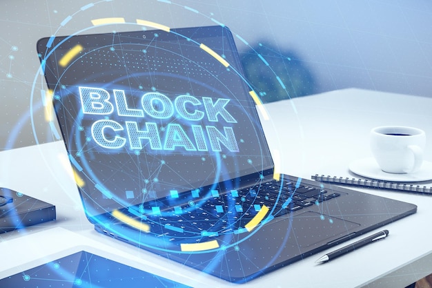 close up of laptop on desktop with abstract blockchain interface cryptocurrency and technology concept double exposure