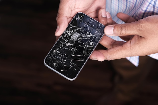 Close up of man hand holding broken smart phone