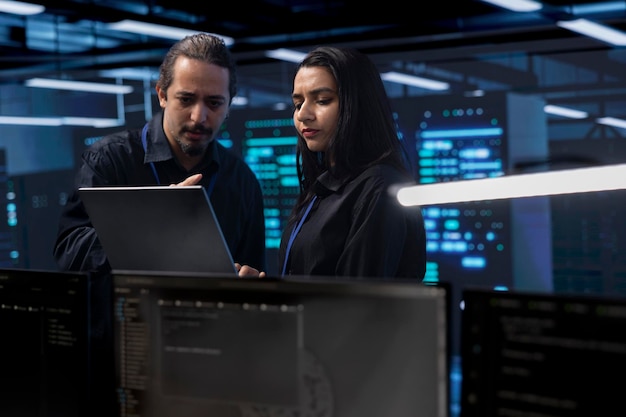 coworkers in data center doing routine disk checks using laptop and tablet