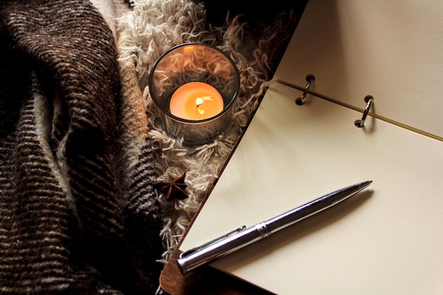 Cozy homely atmosphere a pen and a book Hygge style A mug with a warm blanket candles vintage