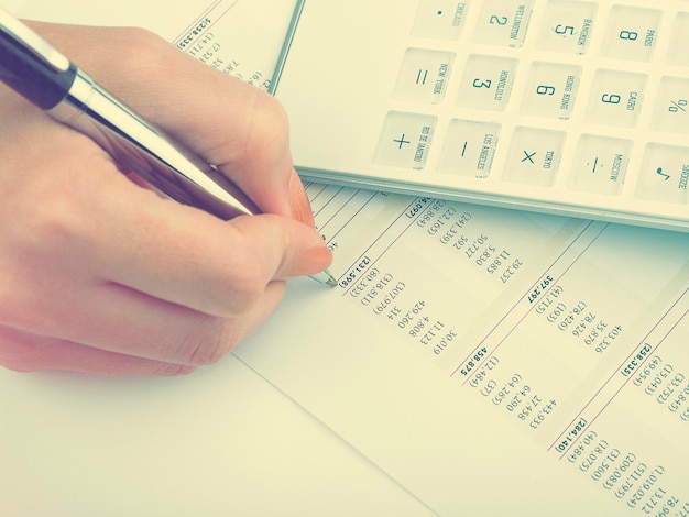 Cropped hand of businesswoman working with document at desk