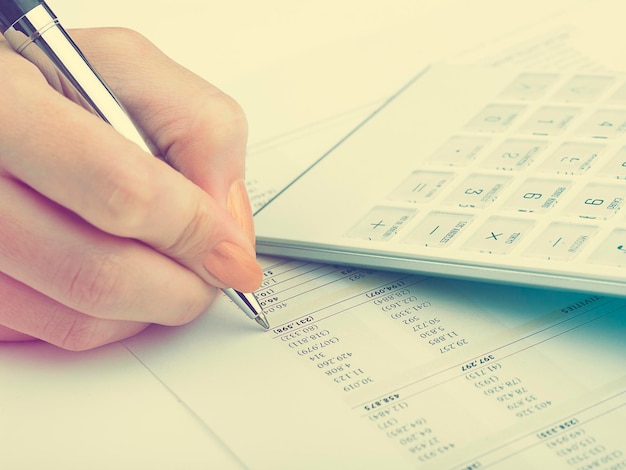 Cropped hand of businesswoman working with document at desk