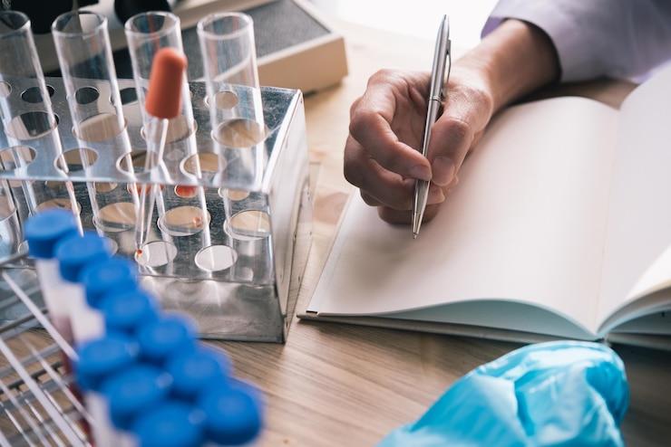 Fotoğraf cropped hand of scientist writing in book at desk