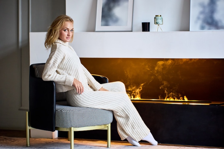 Fotoğraf decorative electric fireplace in lounge and woman sits near