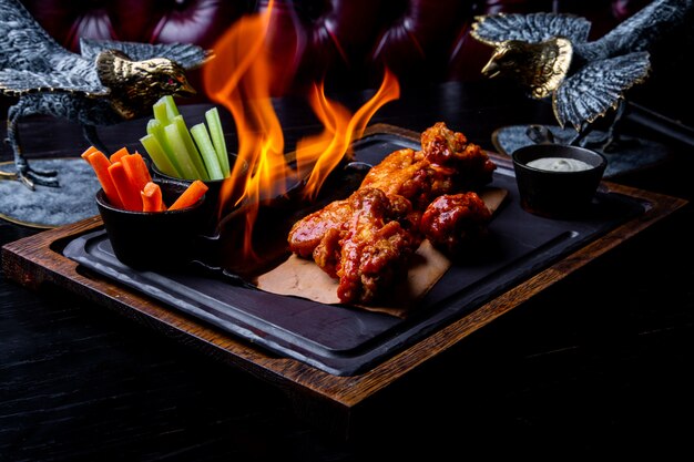 Delicious pieces of chicken wings grilled with Fire flames.  Barbecue and grilling. Restaurant dish