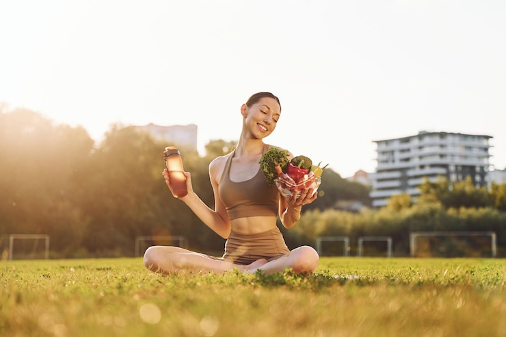 Fotoğraf diet conception healthy food young woman in yoga clothes is outdoors on the field