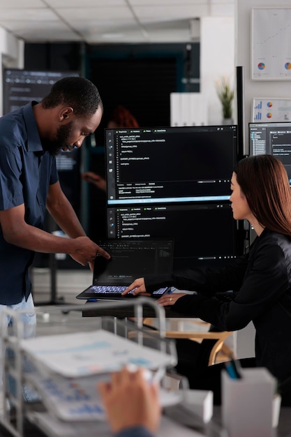diverse team of app developers talking about programming in software company office. artificial intelligence cloud programers compiling code on terminal window server, doing teamwork