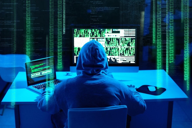 Easily breaching through your firewall Rearview shot of a male hacker cracking a computer code in the dark
