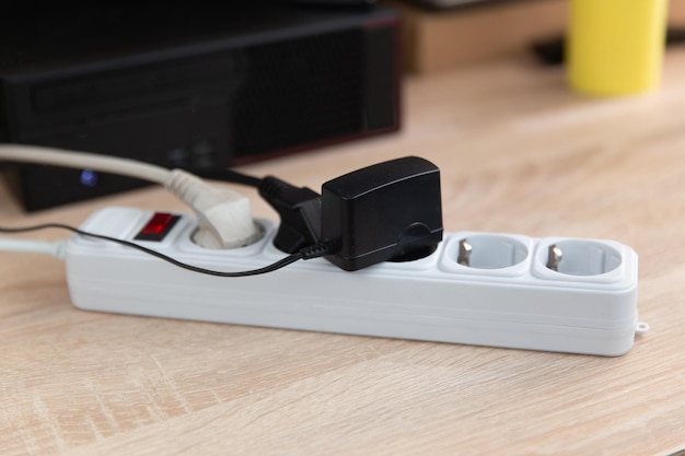 Extension cord with sockets plugs and an adapter on the computer desk