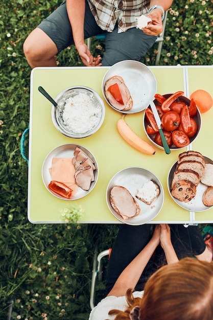 family having breakfast outdoors on camping during summer vacation bread cottage cheese cold meat