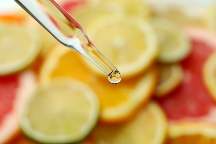 Fotoğraf farklı narenciye dilimlerinin önünde yağlı pipet