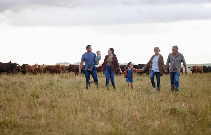 Fotoğraf farming sustainability and family community on a farm walking together with cows in the background happy agriculture countryside group relax holding hands in a green sustainable field in nature