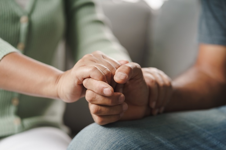 Fotoğraf female friend or family sitting and hold hands during cheer up to mental depress man, psychologist provides mental aid to patient. ptsd mental health concept