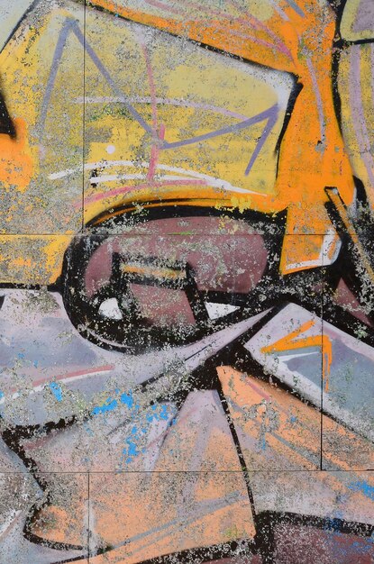 Fragment of graffiti drawings The old wall decorated with paint stains in the style of street art culture Colored background texture in warm tones