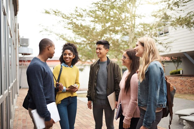 Friends university and students talking before class outside campus together