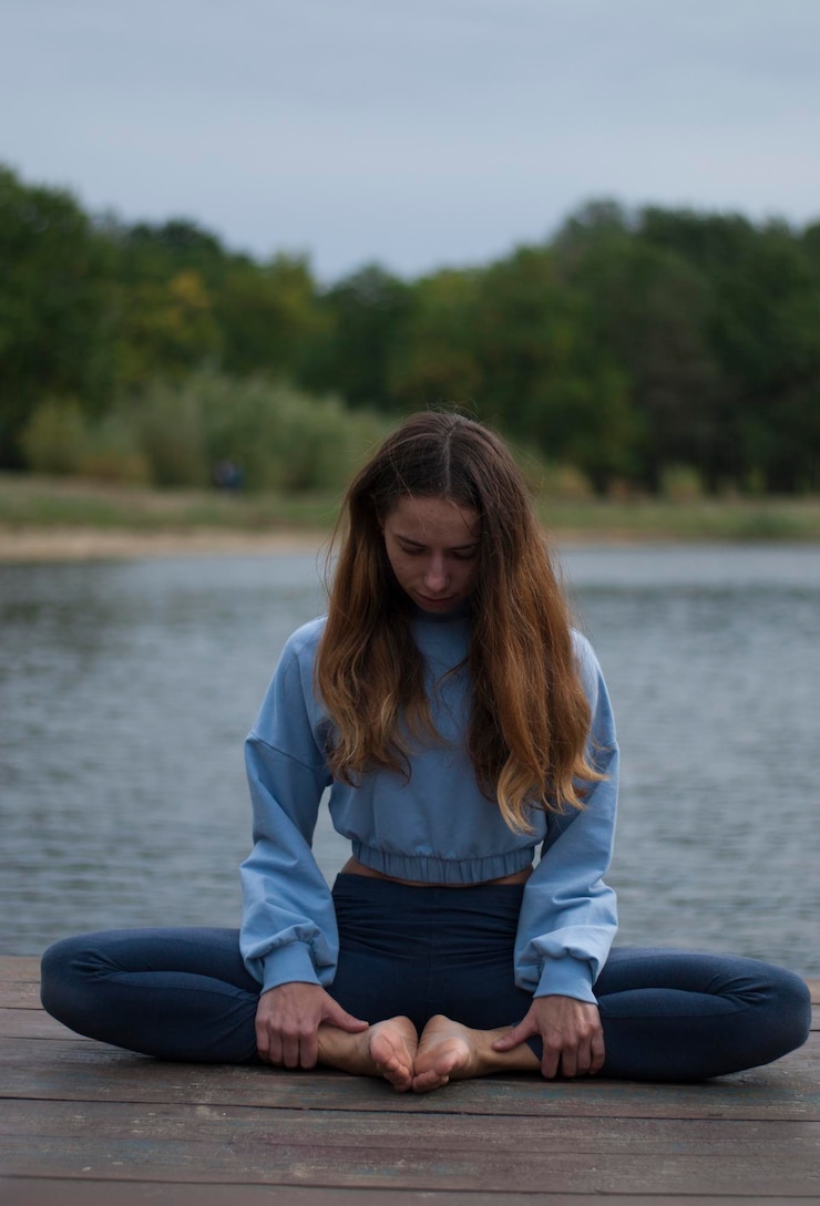 Fotoğraf girl in lotus pose near lake in rainy weather
