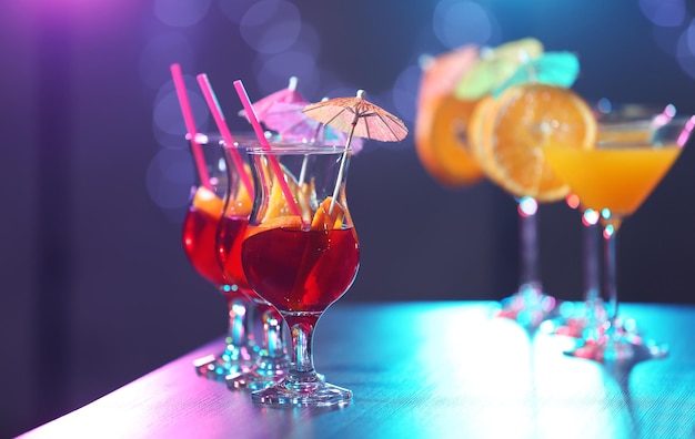 Glasses with tasty cocktails on bar counter against blurred background