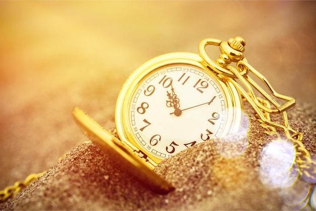 Gold pocket watch in the sand in the sunset