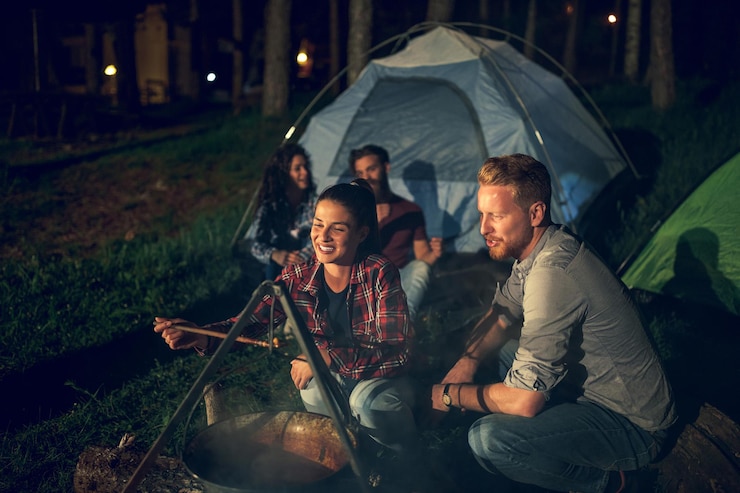 Fotoğraf group of friends cooking stew over a campfire while camping in the woods