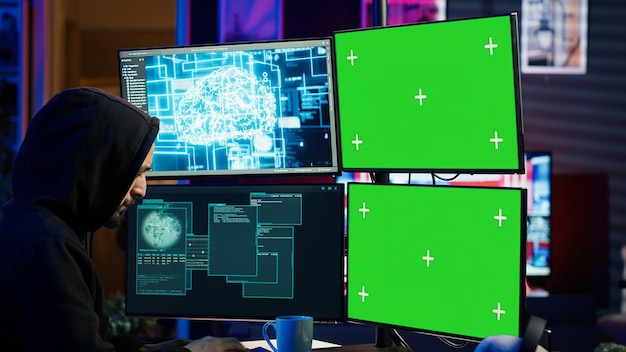 Hacker using AI and green screen computer monitors to produce malicious malware