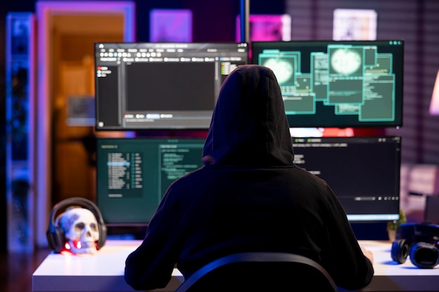 Hacker using exploits on computer to break into systems and access restricted data hooded man using
