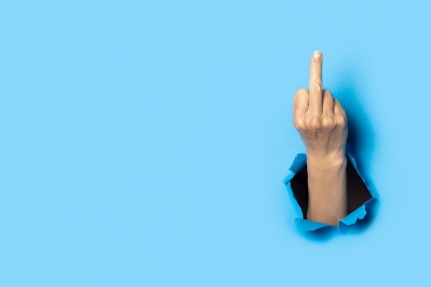 hand shows the gesture of the middle finger on blue