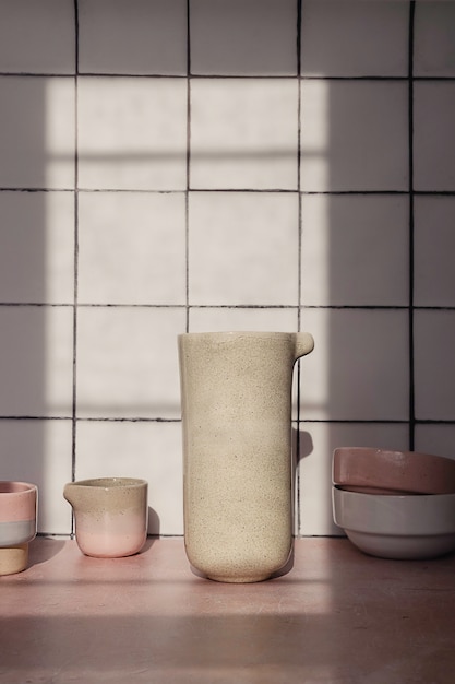 handmade empty tableware such as ceramic jars, mugs and dishes composition on a white kitchen tile.