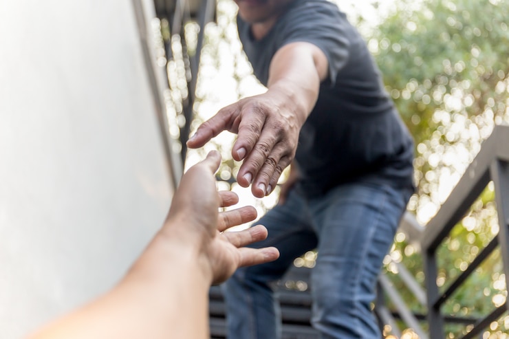 Fotoğraf help concept hands reaching out to help each other with bokeh background.