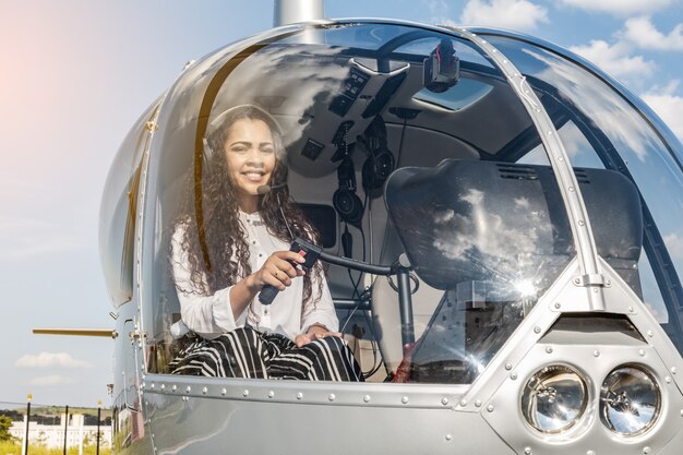 Kalkıştan önce helikopterin kokpitinde kadın pilot. Genç kadın helikopter pilotu.