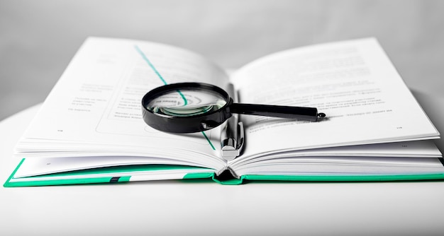 Magnifier over open business paper book concept of knowledge and studying