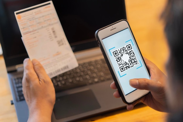 Male hand holding a mobile phone to scan the QR code for the bill through the app