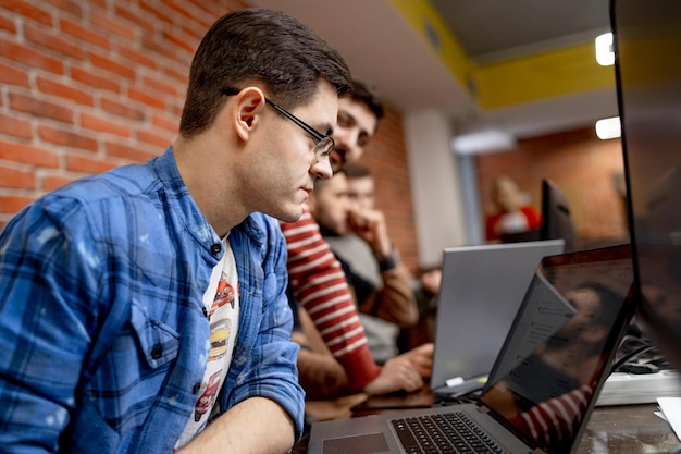 Male programmer working on desktop computer near monitor at office in software development company. Website design programming and coding technologies