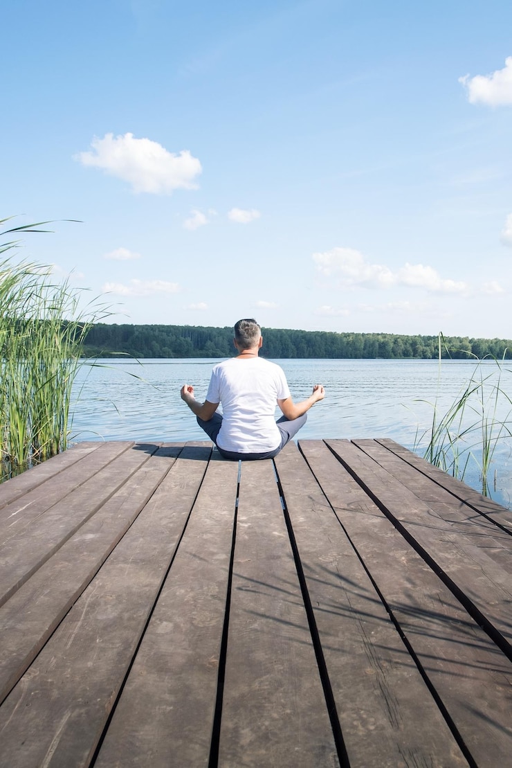 Fotoğraf man meditating near river back view