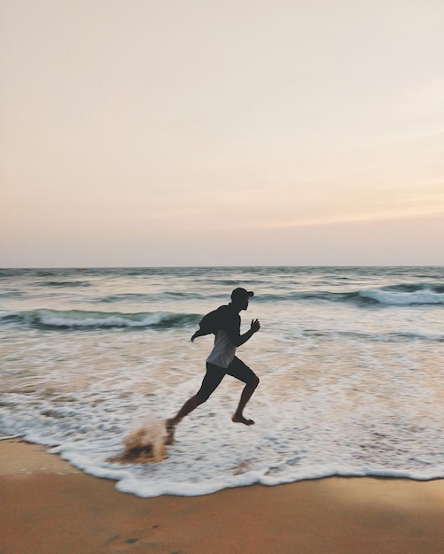 man on beach against sky during sunset
