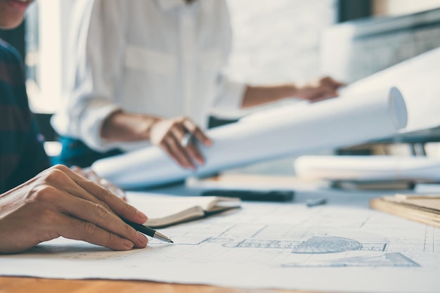 Midsection of engineers working over blueprint on table at office