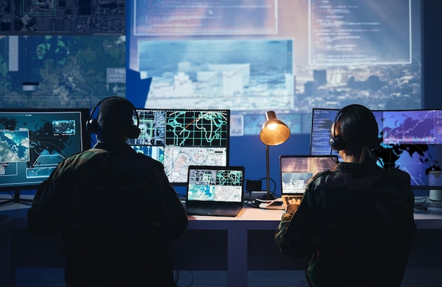 Military control room computer screen and team with surveillance headset and tech communication from back Security satellite map and man with woman at monitor in army office at command center