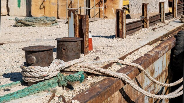 Mooring ropes tied on a rusty steel bollard on a deck Old industrial harbor quay