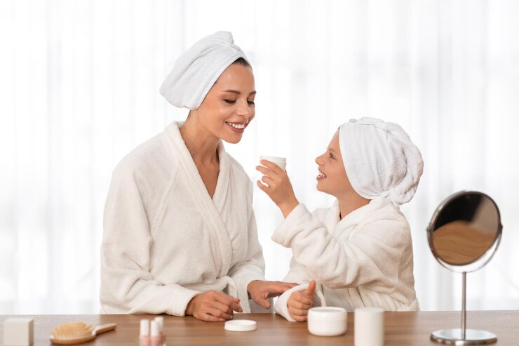 Fotoğraf mother and daughter in bathrobes doing skin care routine at home