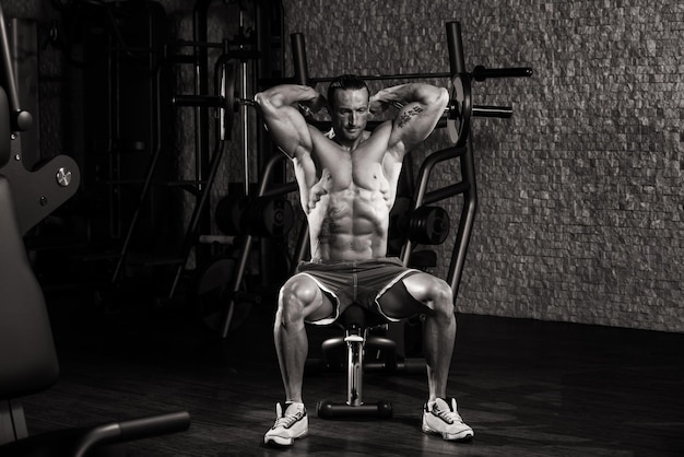 Muscular Mature Man Doing Heavy Weight Exercise For Triceps In Modern Fitness Center