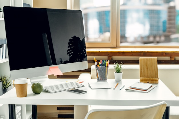Ofis veya ev çalışma alanı. Ofis masasında malzemelerle birlikte siyah ekranlı bilgisayar monitörü