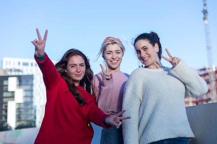 Fotoğraf portrait of friends gesturing peace sign in city