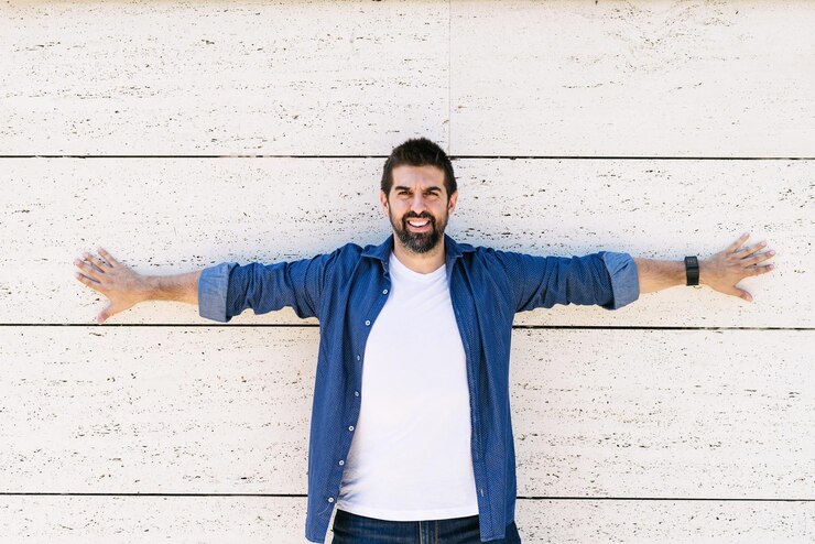 Fotoğraf portrait of smiling young man standing against wall
