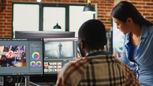 Professional video editors analyzing film montage before editing color grading and lighting, doing teamwork in creative office. Post production house employees working with video footage.