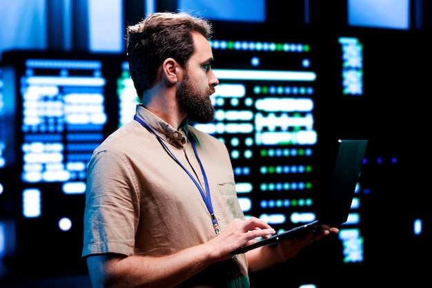 Proficient technician using laptop to check server hub devices. High tech rigs in data storage and cloud computing business service providing processing for several workloads